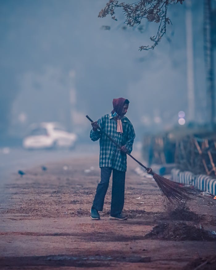 A street sweeper cleans a foggy urban street, adding to the early morning city hustle.